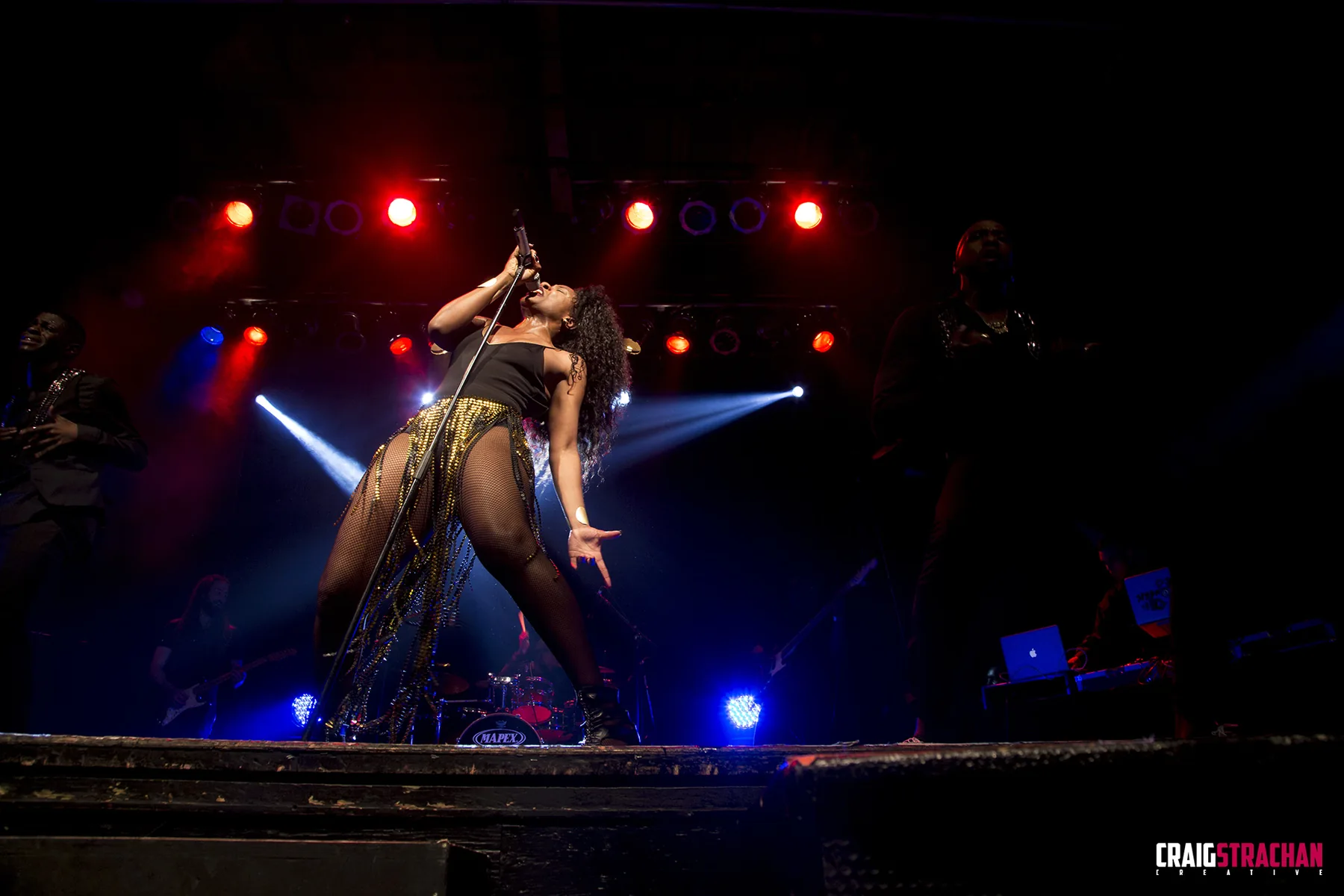 Live performance photograph on a dark stage with dramatic lighting.
