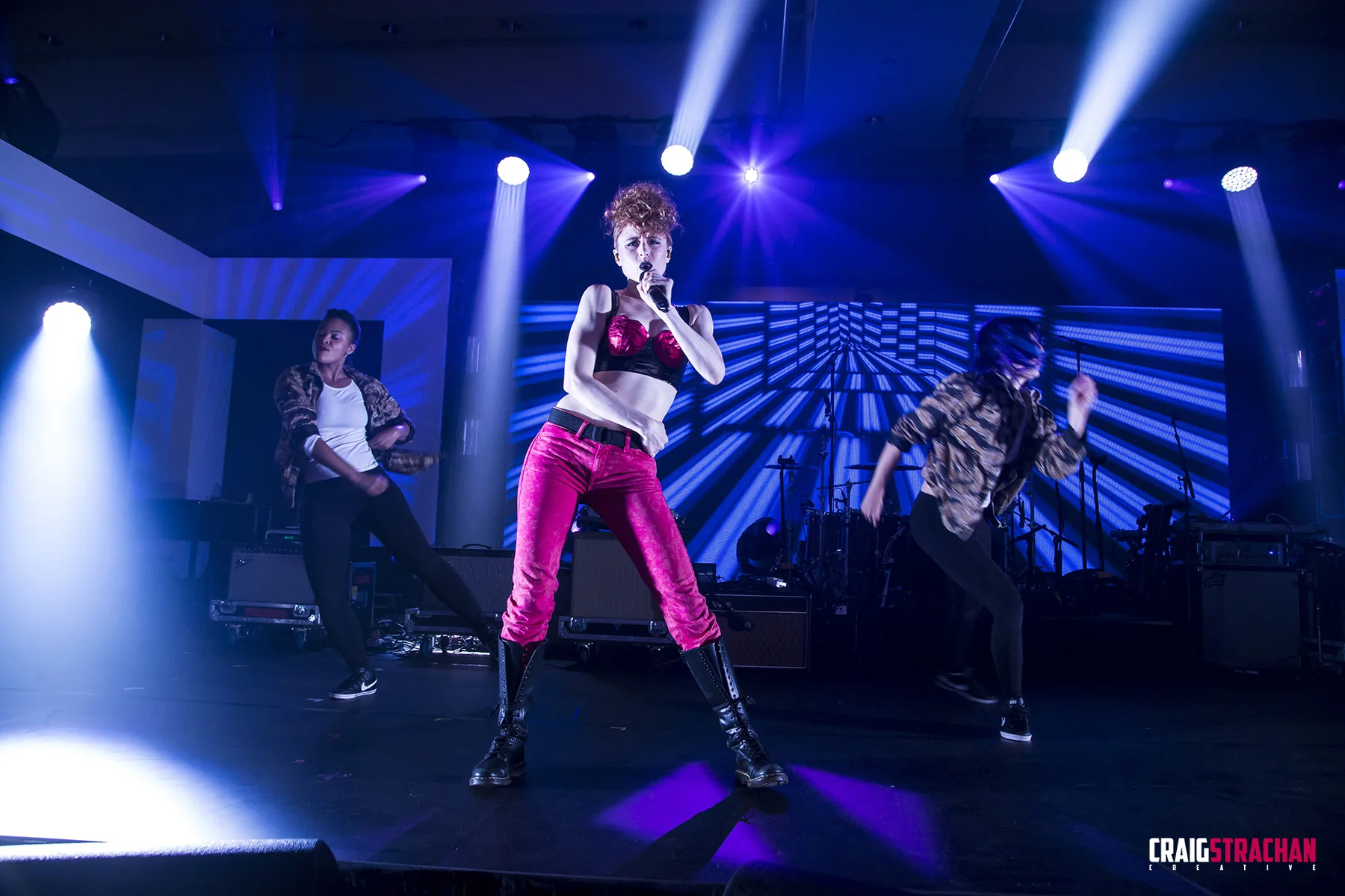 Live concert photograph under blue and purple stage light.